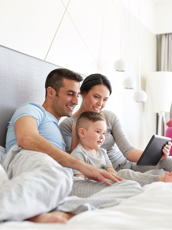 Family lounging in bed looking at tablet